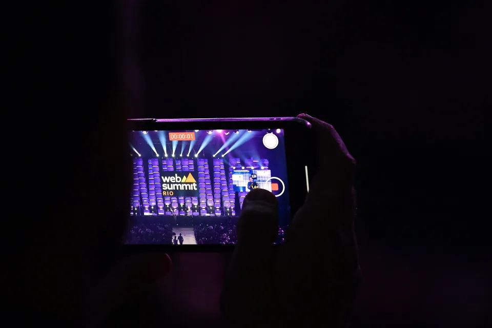 Person filming with a mobile phone at Web Summit Rio in Rio de Janeiro