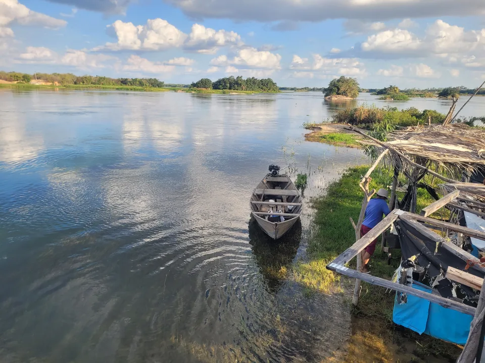 Pequeñas barcas junto a un embarcadero fluvial con aguas tranquilas e islas al fondo